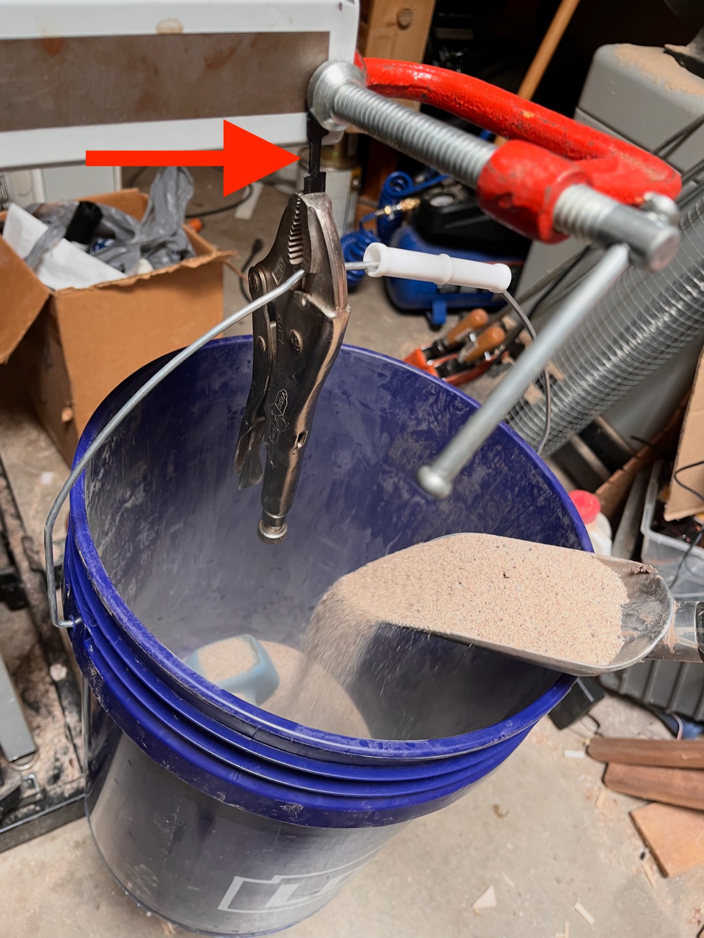 Tensile test of a 3D-printed plastic sample hanging from a clamp over a bucket of sand